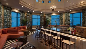 A spacious, well-lit interior with a large seating area, a bar, and a view of the sky through a skylight.