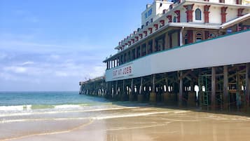 A beachfront building with a sign reading "EAT AT JOE'S" and a pier extending into the ocean.