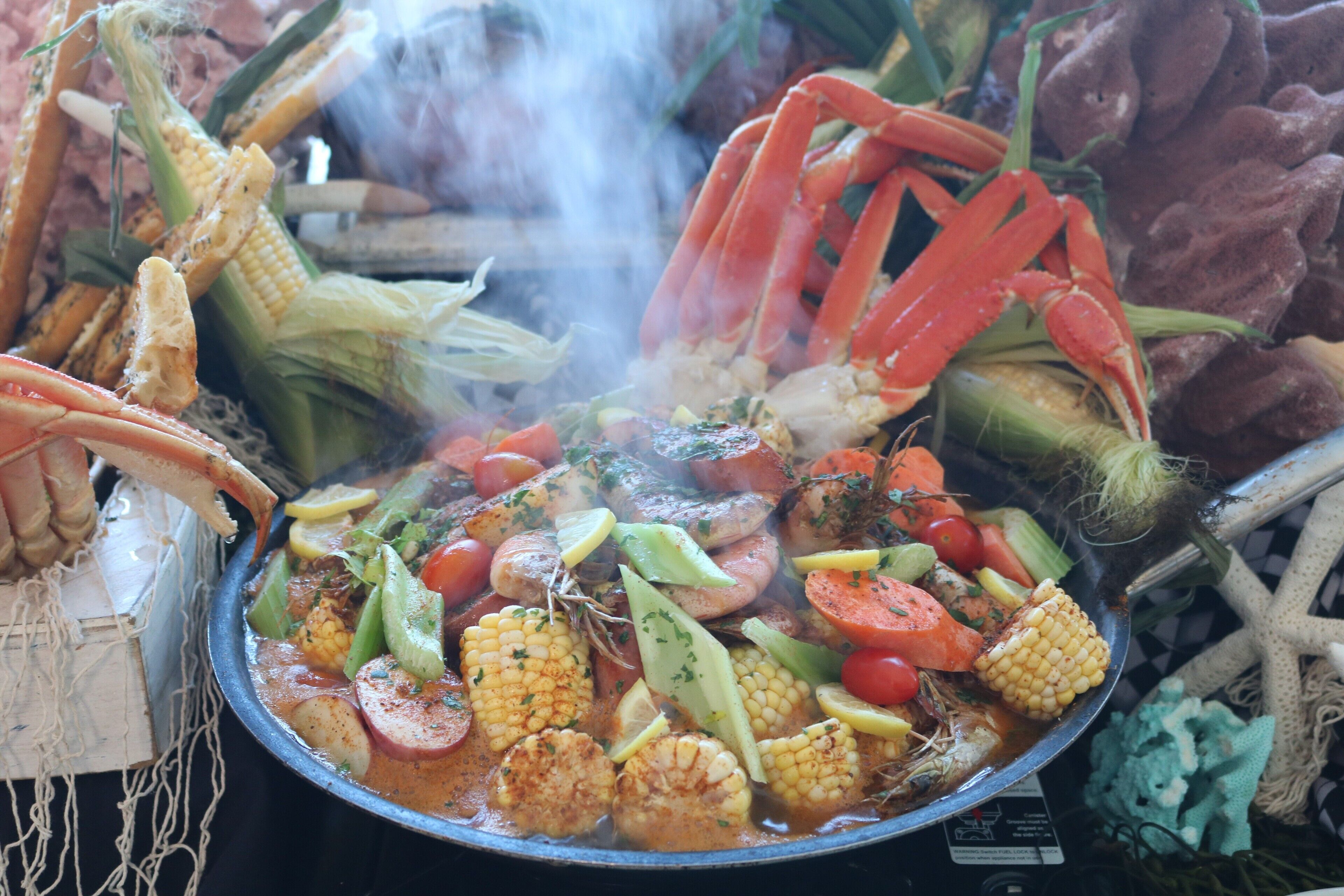 A seafood dish with corn, tomatoes, and various vegetables.