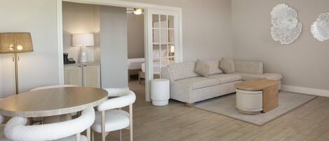 A modern living room with a round table, white cushioned chairs, a sofa, and a coffee table.