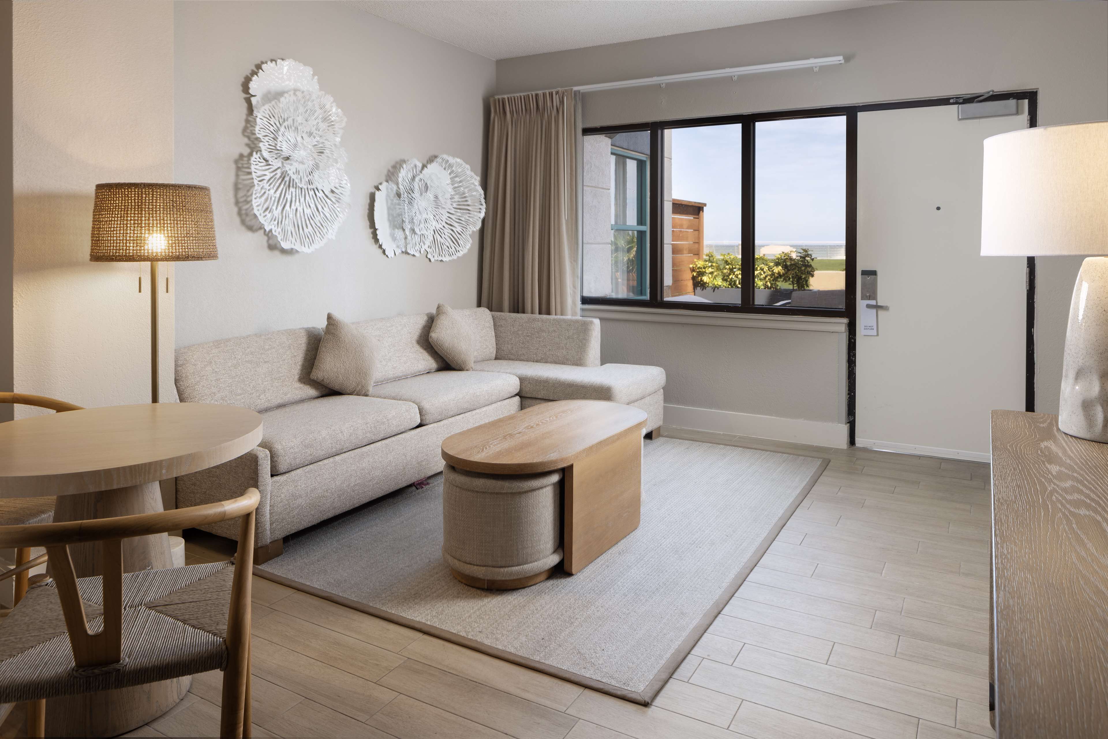 A modern living room with a sofa, a round table, a small side table, and a lamp.