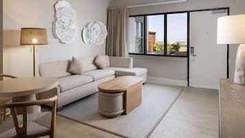 A modern living room with a sofa, a round table, a small side table, and a lamp.