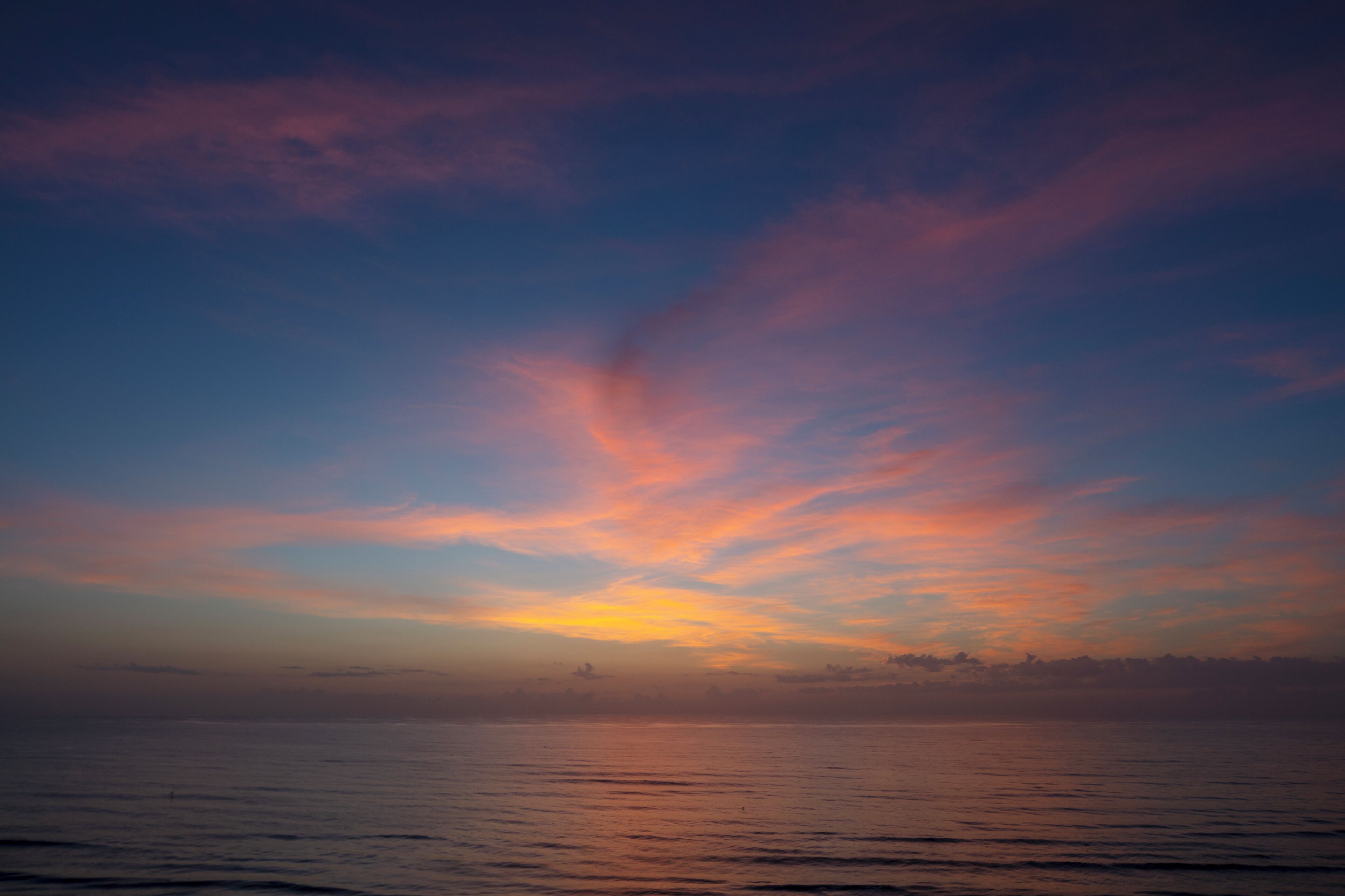 A sunset over a calm sea with a clear horizon.