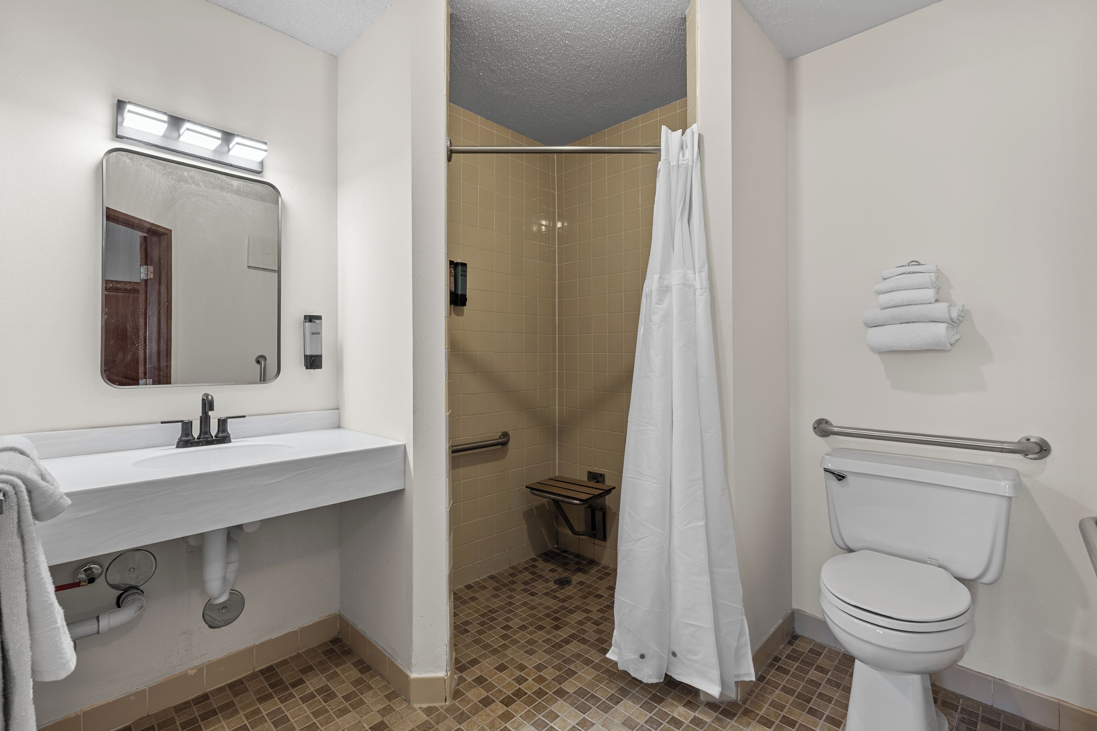 Une salle de bain équipée d’un lavabo, d’un miroir, de toilettes, d’une douche et d’un porte-serviettes.