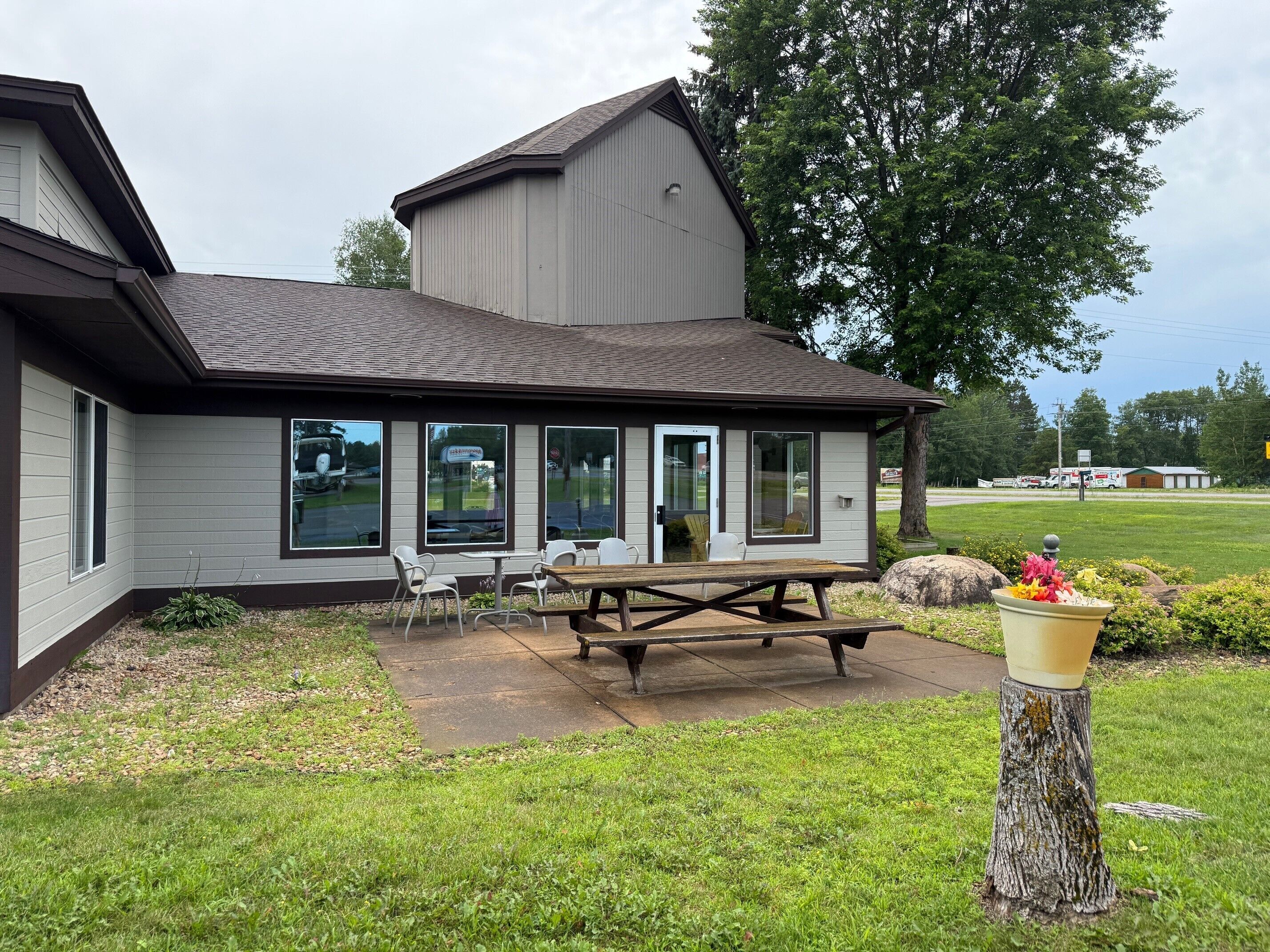 A building with a covered patio area, large windows, and a picnic table.