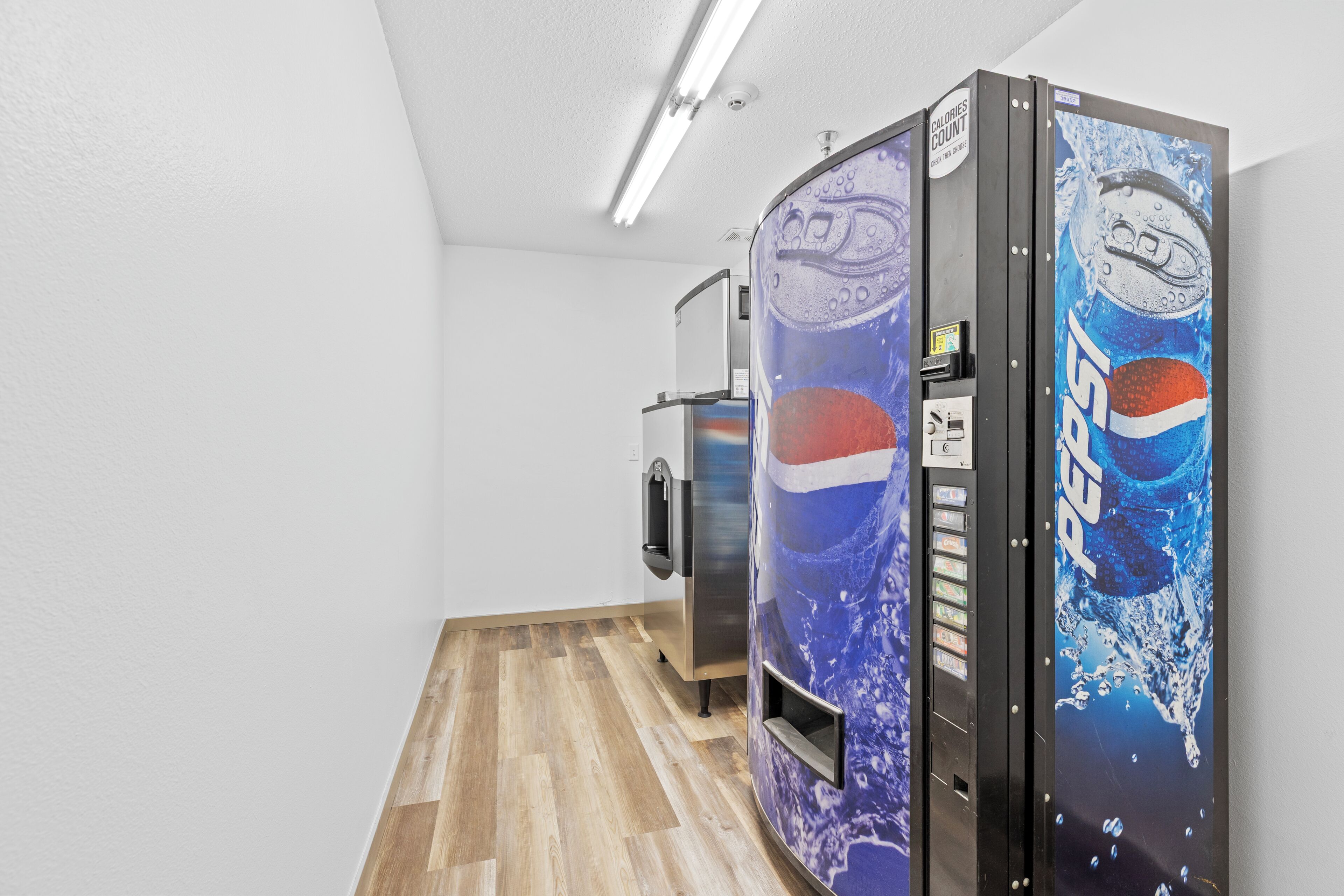Een gang met automaten, waaronder een Pepsi-koelkast en een waterkoeler.