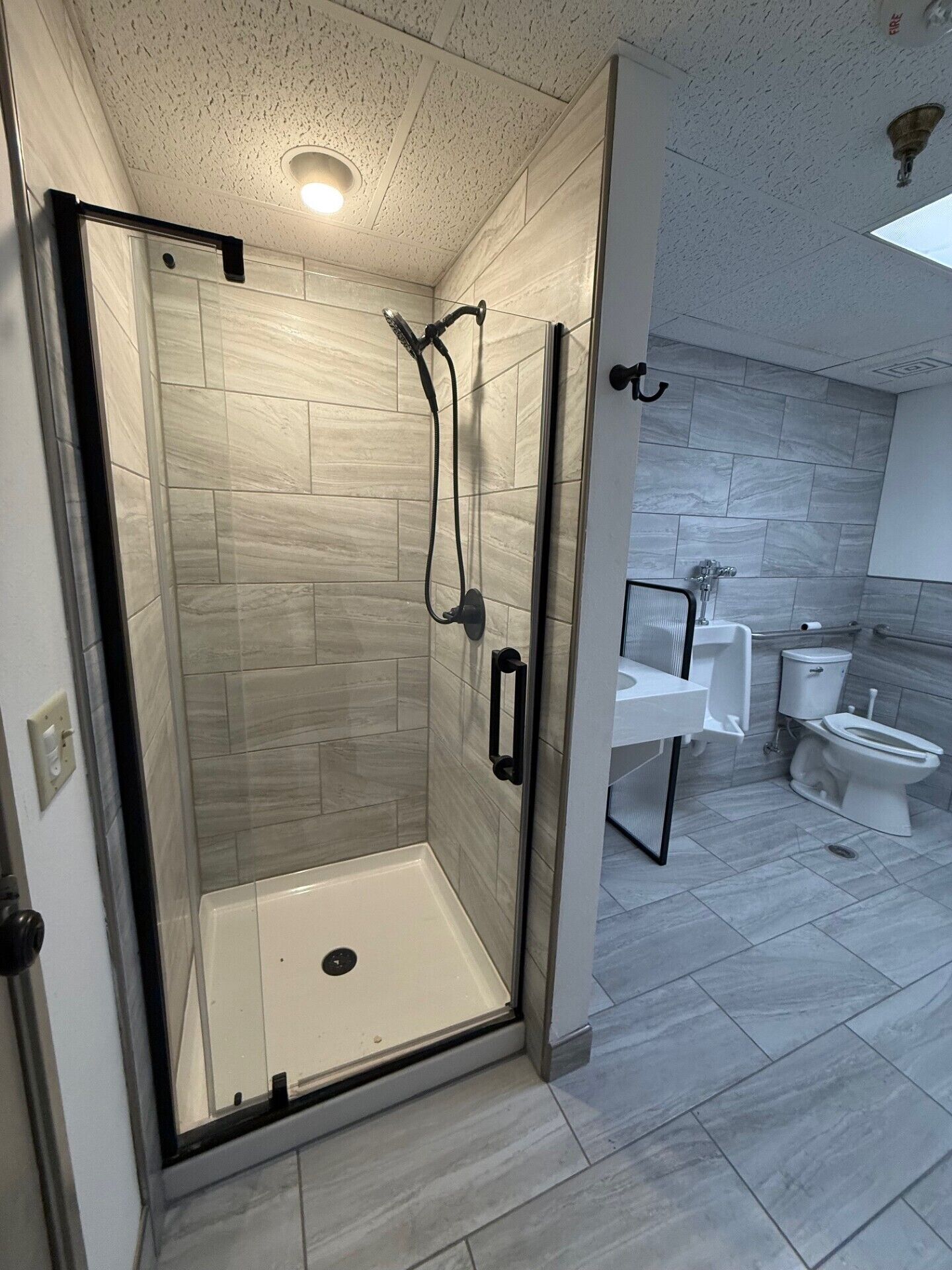 Een moderne badkamer met een douchecabine van glas, een witte wastafel en een toilet.