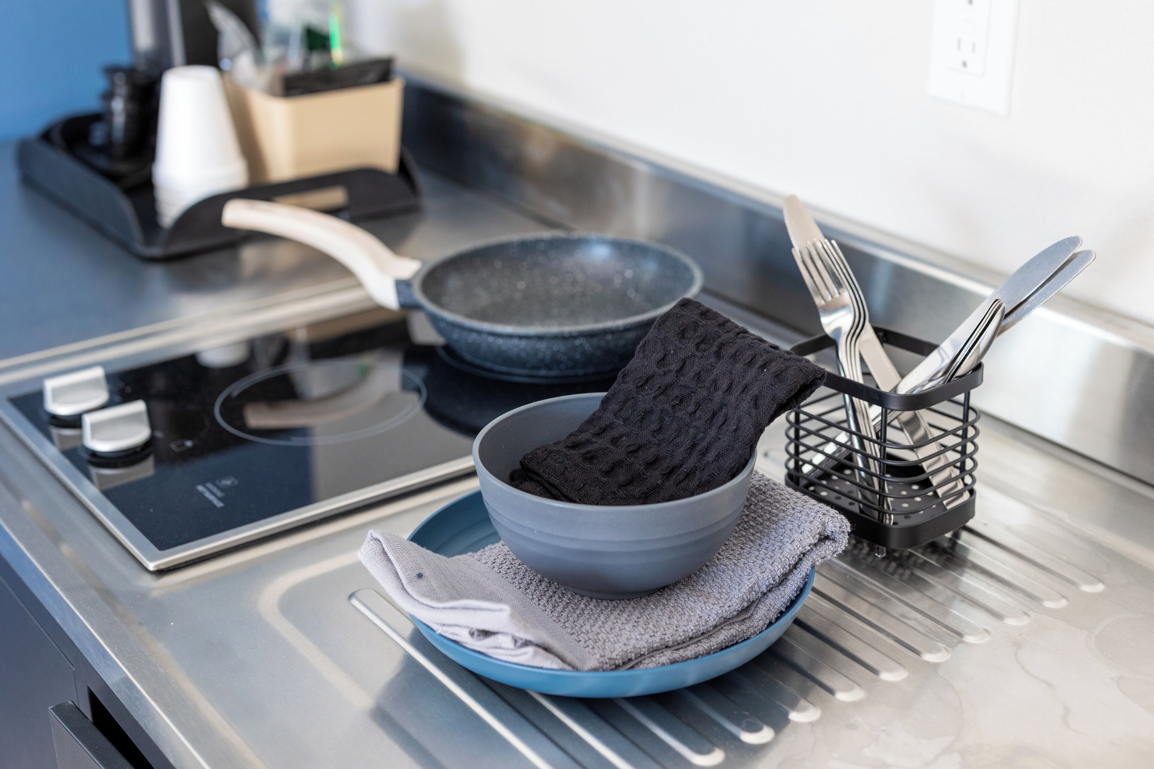 A kitchen with a stove, a bowl, a plate, and a utensil holder.