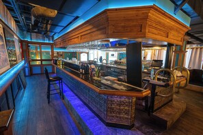 A bar area with a wooden counter, bar stools, and a wine rack.