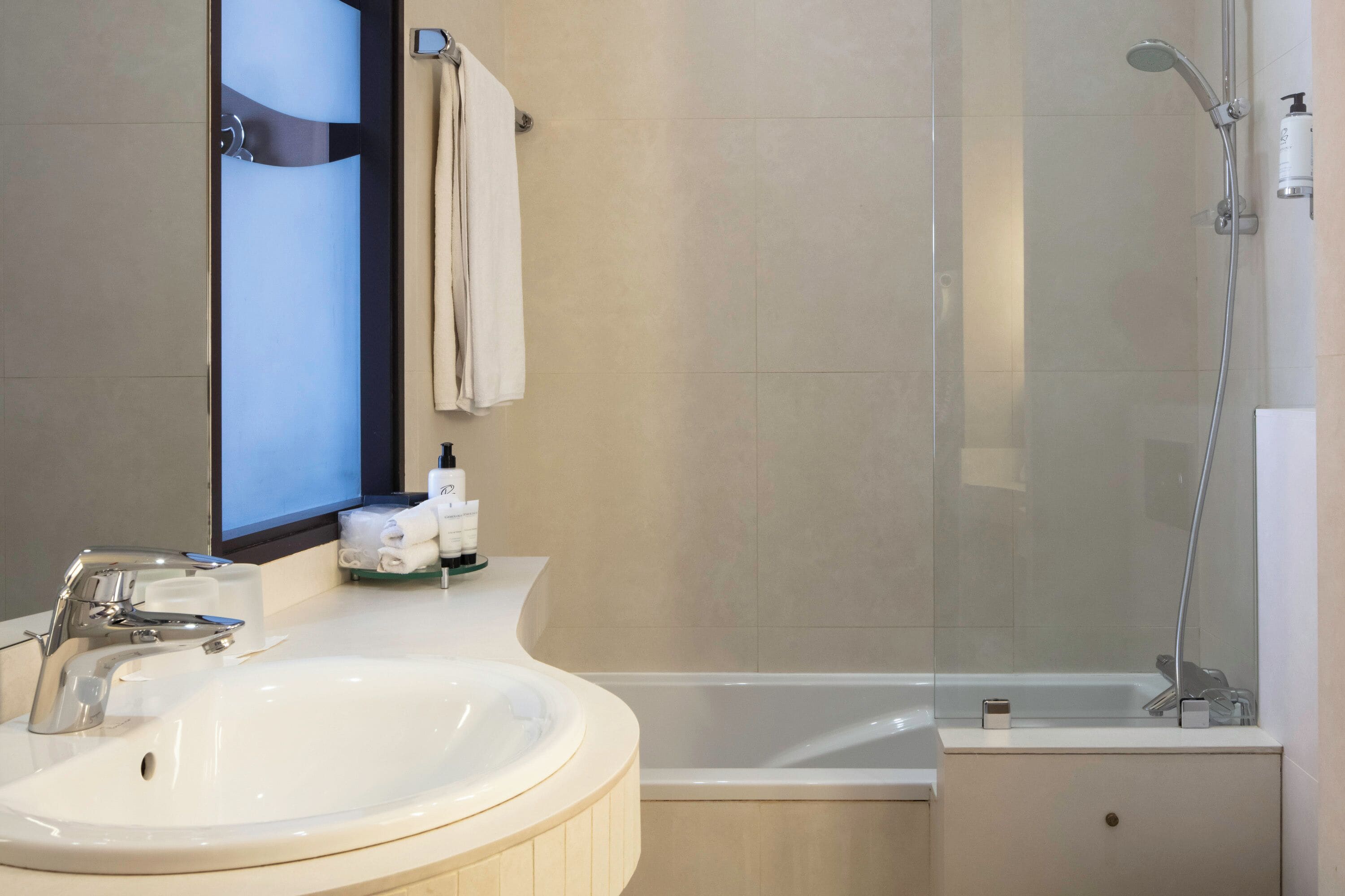 A modern bathroom with a white sink, a glass-enclosed shower, and a bathtub.