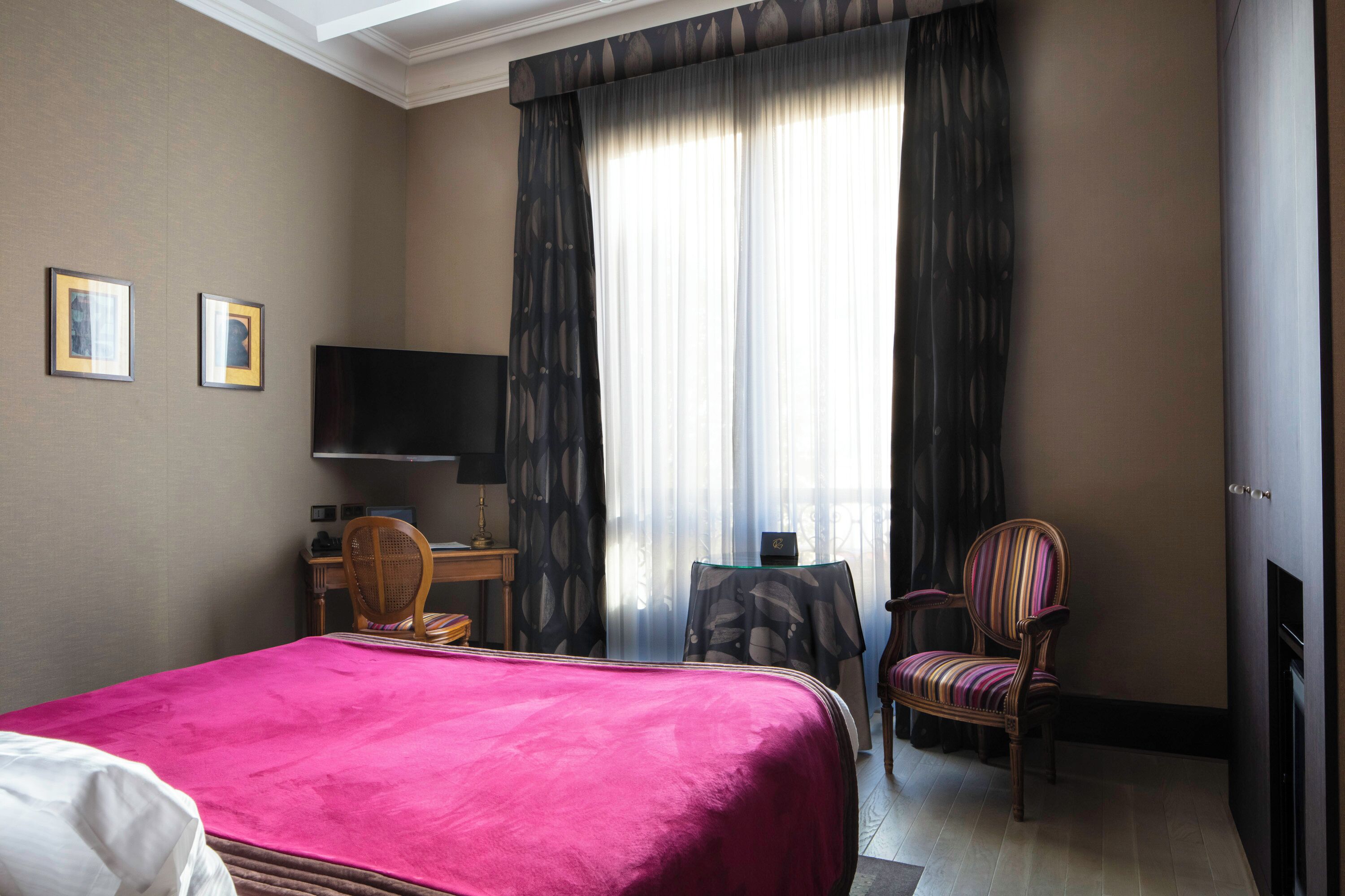 Une chambre d’hôtel équipée d’un lit, d’un bureau, d’une chaise, d’une télévision et d’une cheminée.