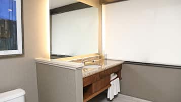 A bathroom with a granite sink, wooden vanity, and a large mirror.