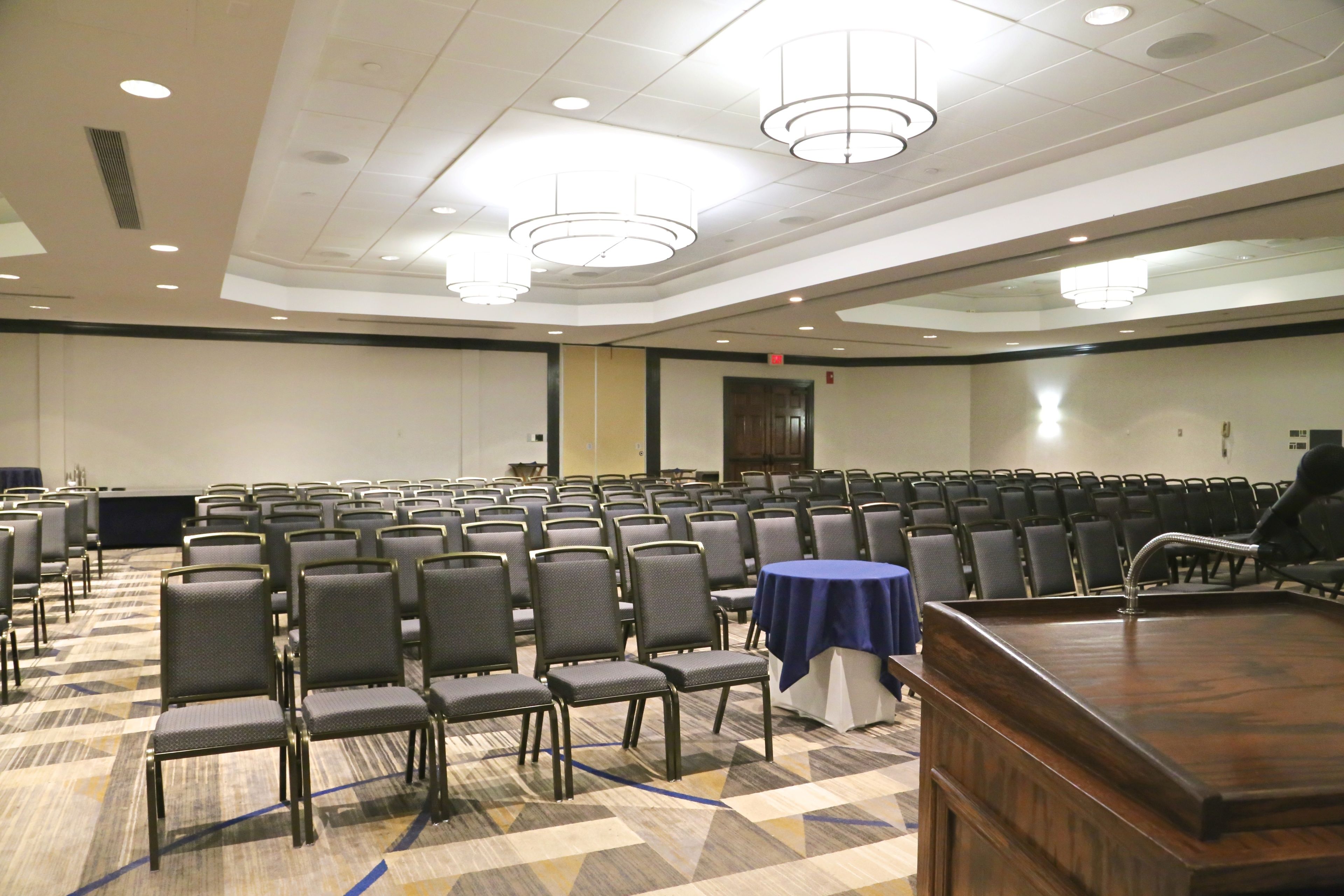 A conference room with rows of chairs, a podium, and a carpeted floor.