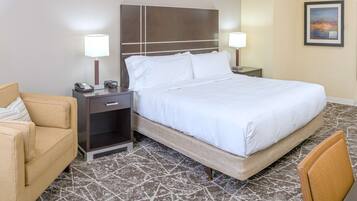 Habitación de hotel con una cama grande, dos mesitas de noche con lámparas, un sofá y una alfombra estampada.