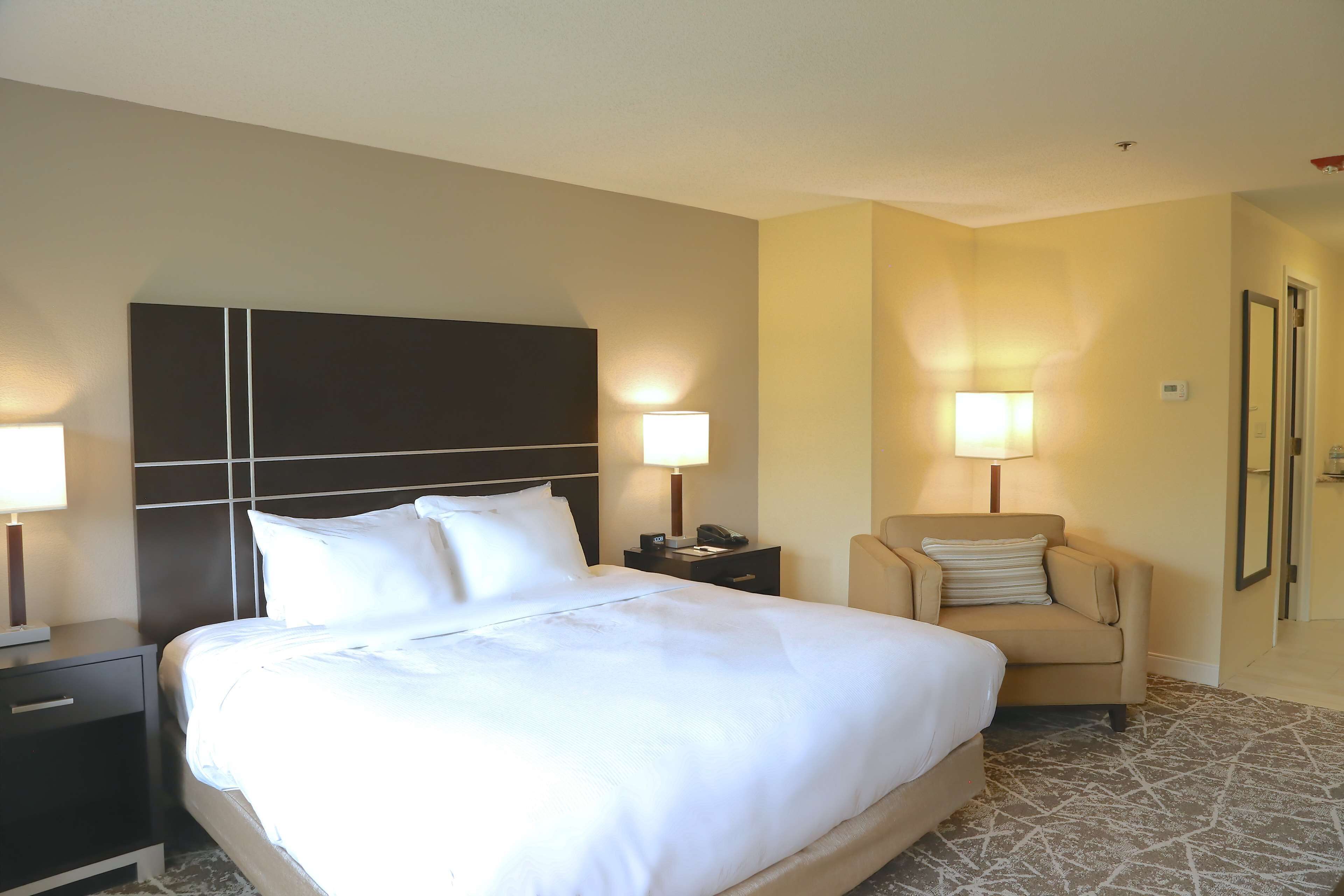 Camera d'albergo con un letto grande, due comodini, una poltrona e due lampade a parete.