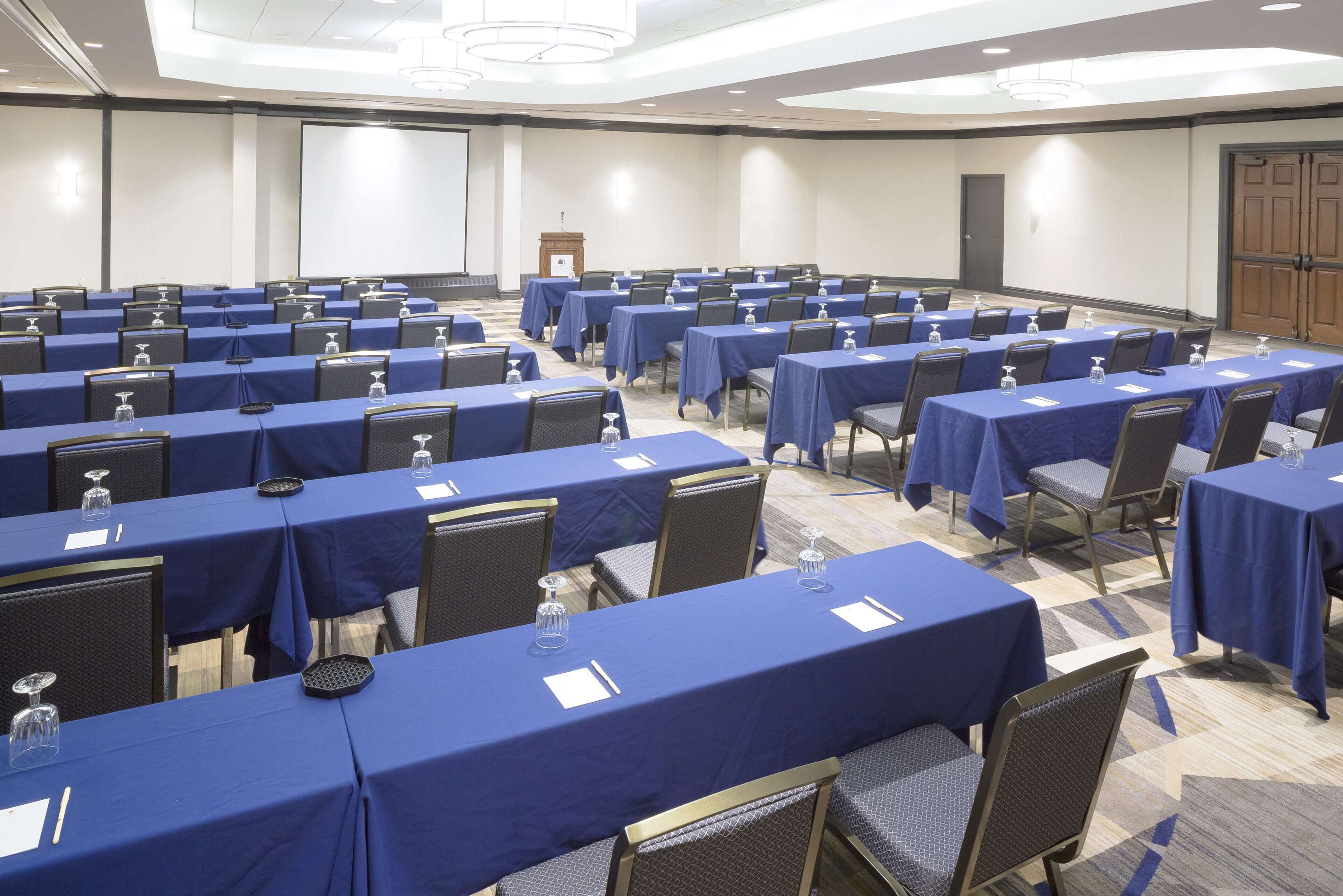 A conference room with rows of tables and chairs, equipped with water bottles and name cards.