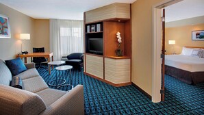 Habitación de hotel con sofá, televisión, una mesita, sillón y cama.