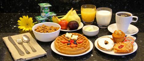 A breakfast setting with various food items and drinks on a kitchen counter.