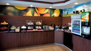 Una barra de desayuno con diversos alimentos y un dispensador de zumo.