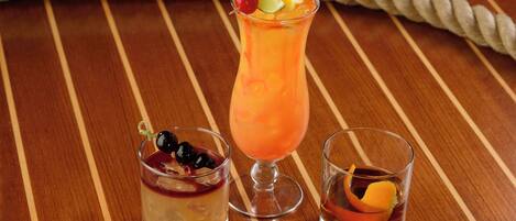 Three drinks on a wooden table with a rope in the background.