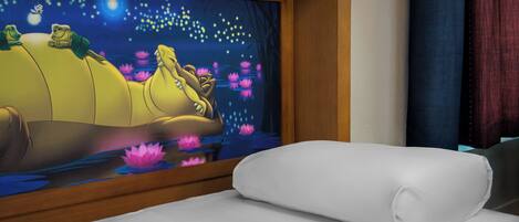 Habitación de hotel con una cama, un mural grande en la pared que muestra una escena nocturna con ranas y flores de loto, y un cabecero de madera.