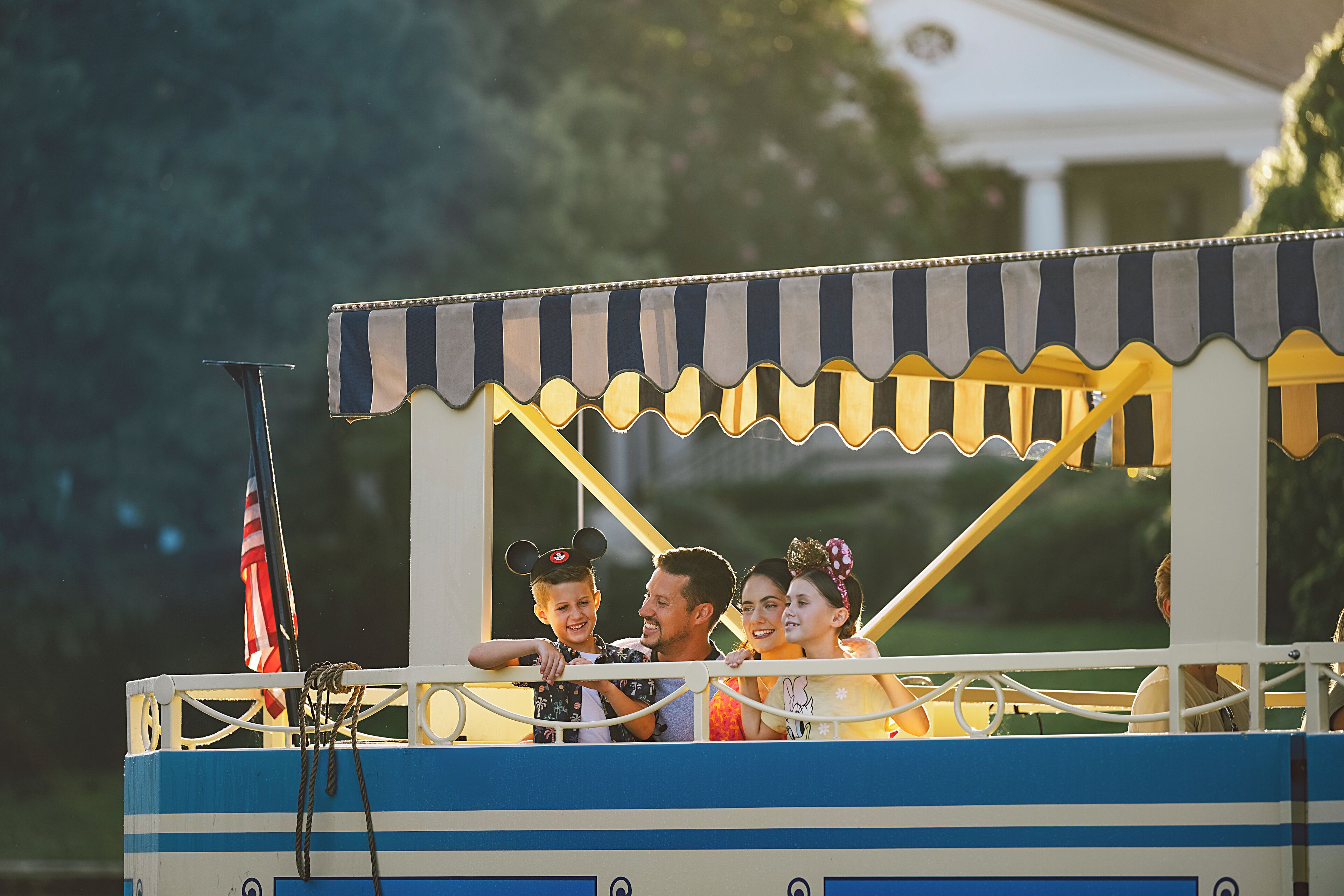 A boat with a striped awning and a flag, passengers on board, and a railing.