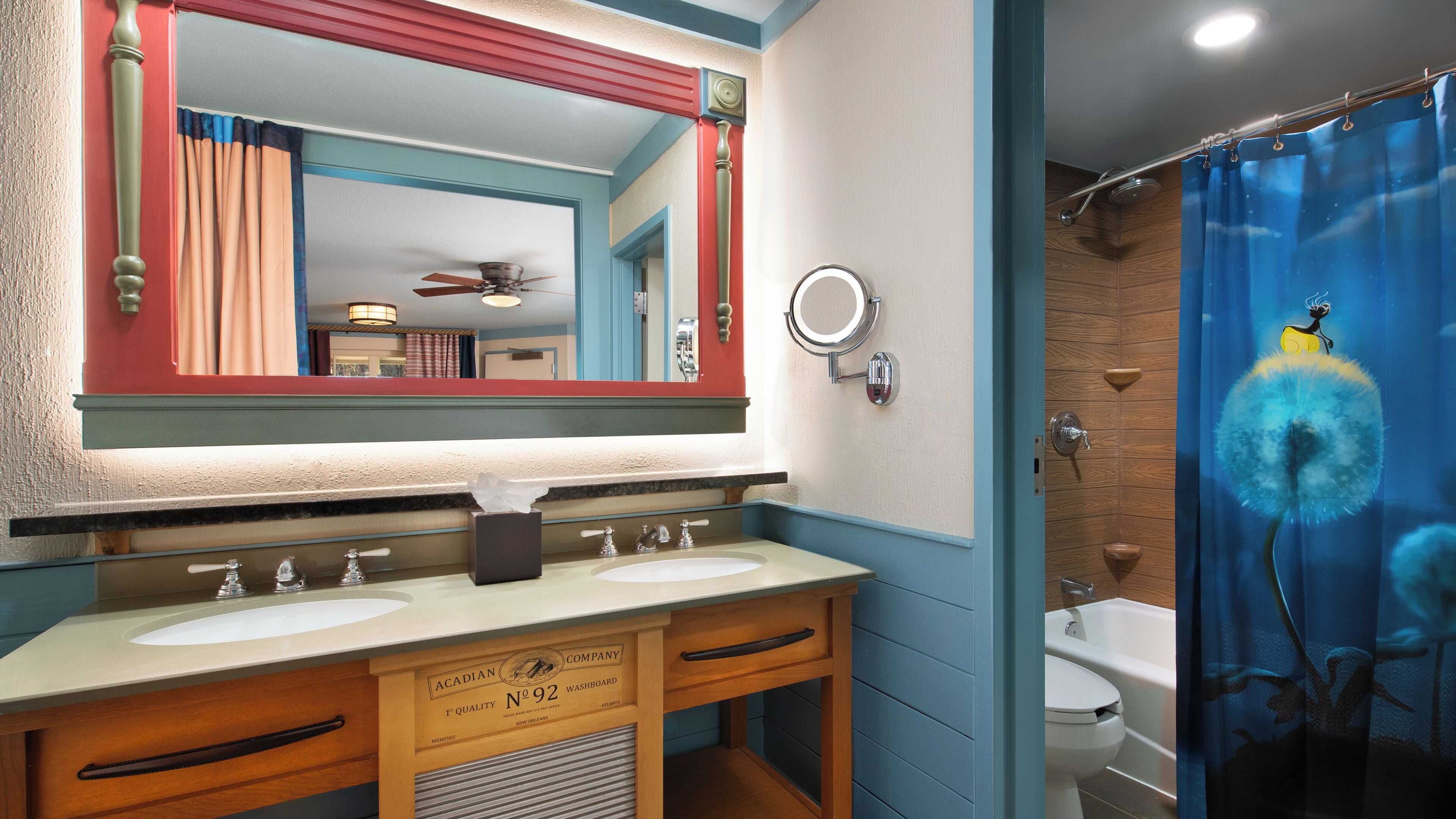 Un baño con dos lavamanos, un espejo, una cortina de ducha con diseño de diente de león y un ventilador de techo.