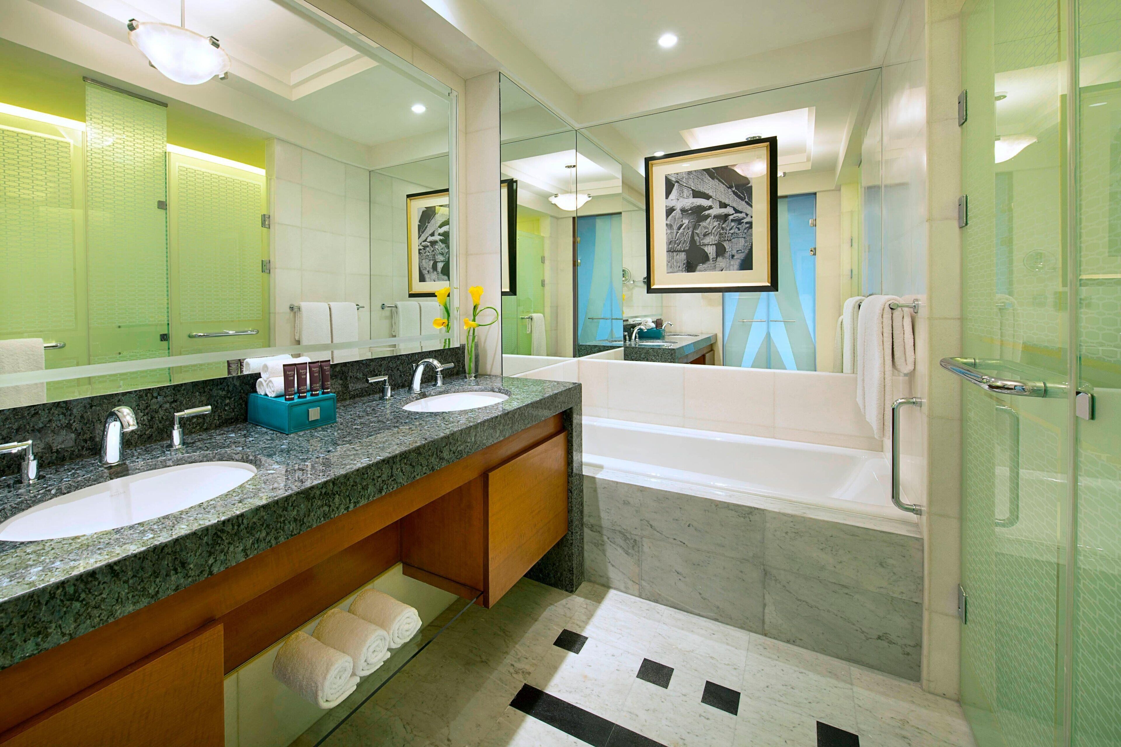 A modern bathroom with two sinks, a bathtub, and a glass shower enclosure.
