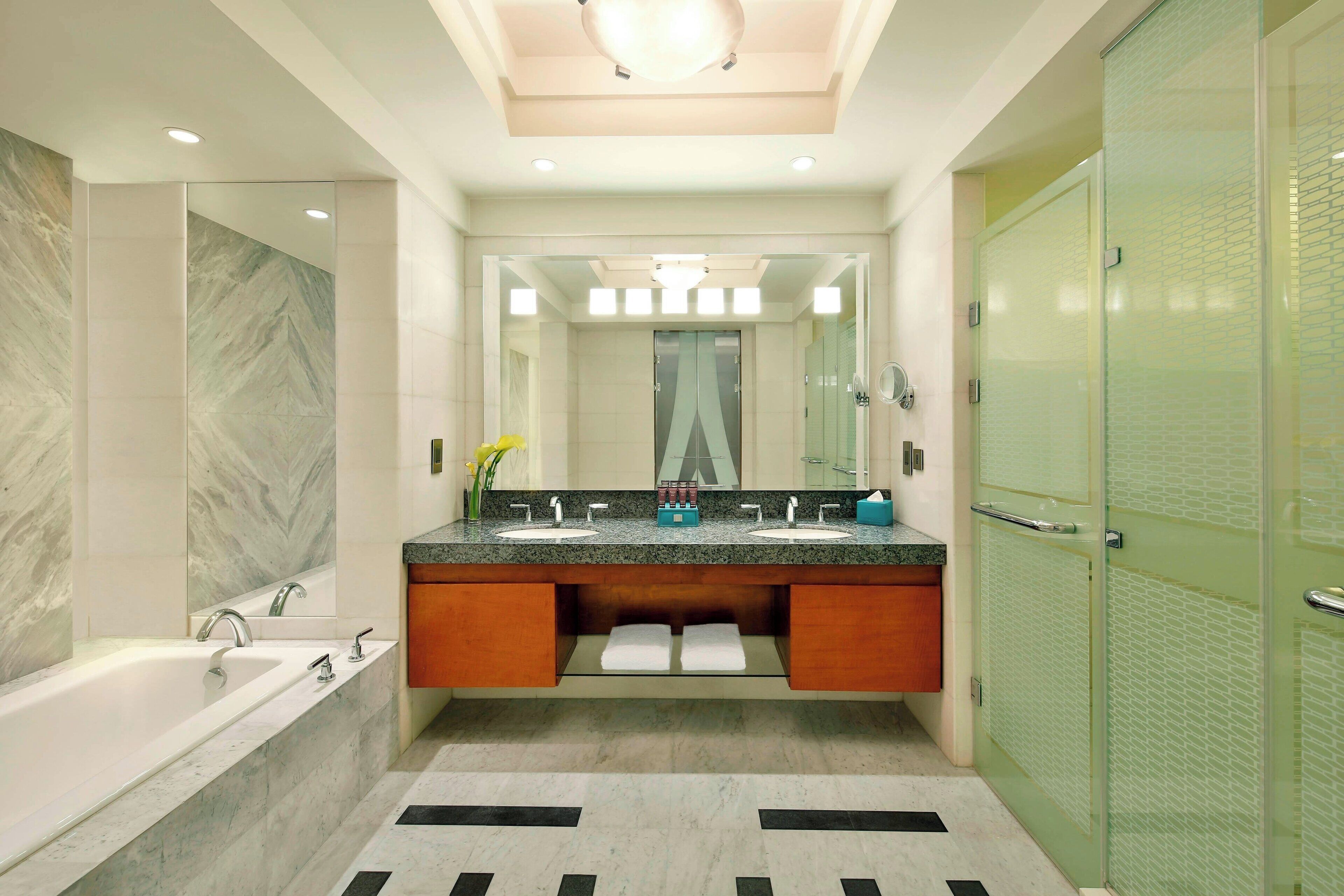A modern bathroom with a large bathtub, double sinks, and a glass-enclosed shower.