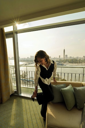 A person standing by a window with a view of a river and cityscape. - The Nile Ritz-Carlton, Cairo (Cairo)