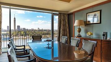 A conference room with a large glass table, chairs, a coffee machine, and a view of a city skyline.