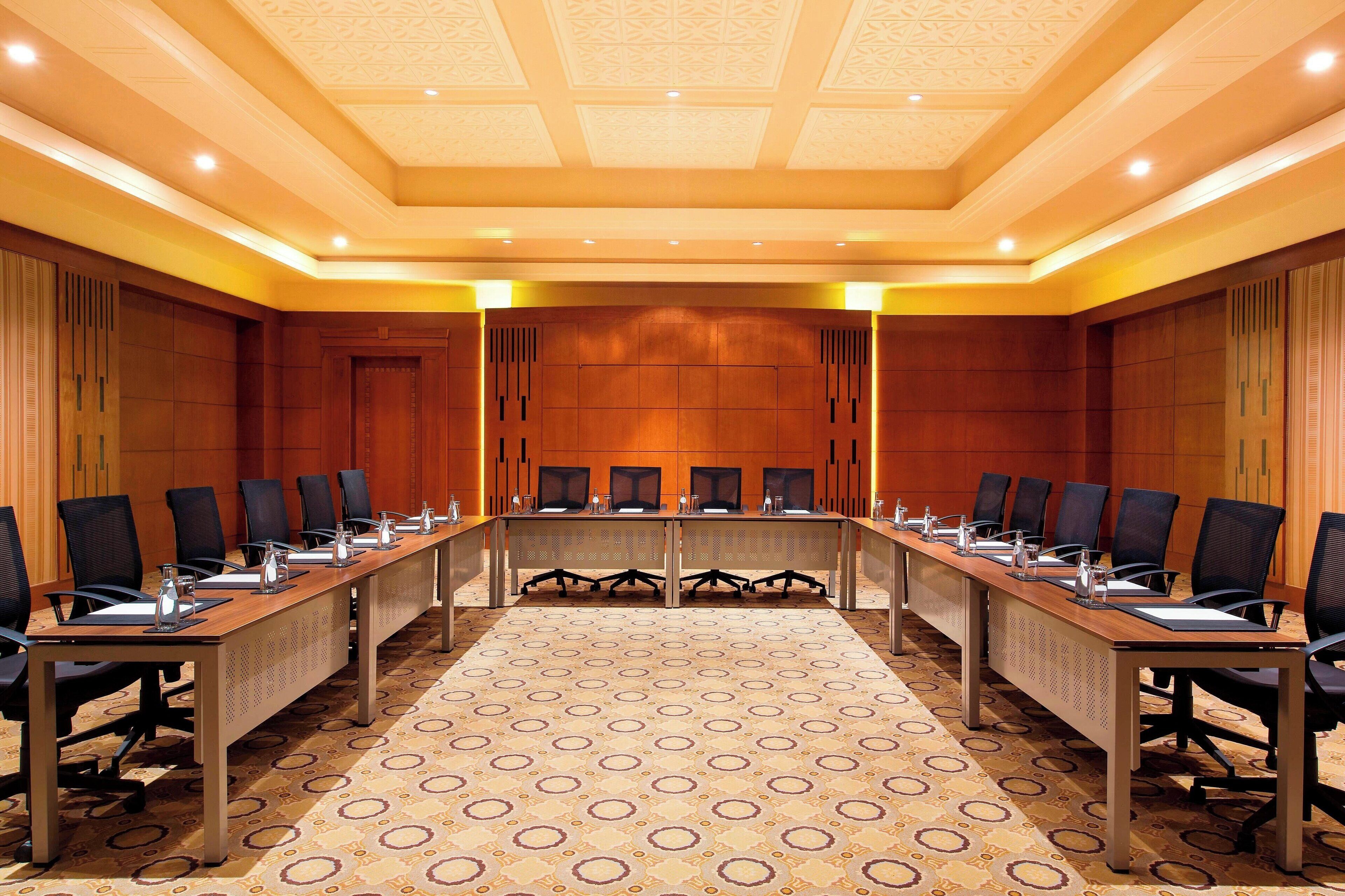 Una sala de conferències amb una taula llarga, diverses cadires i una catifa estampada.