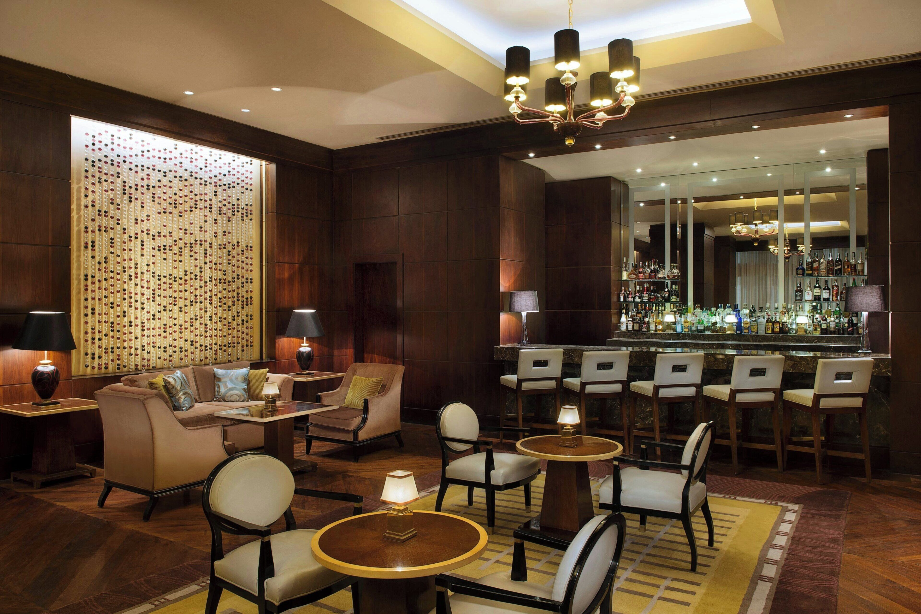 A hotel lobby with a bar, seating arrangements, and a decorative wall.