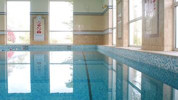 Ein heller, überdachter Pool mit Fliesenwänden und einem Fenster.