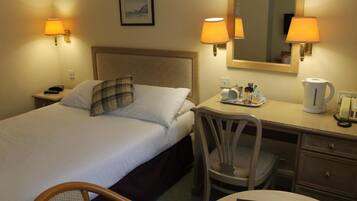 A hotel room with a bed, a desk, a chair, a mirror, and a nightstand.