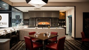 A modern hotel lobby with a central island, red chairs, a marble countertop, and a large overhead light fixture. - DoubleTree by Hilton Hotel Bristol, Connecticut (Bristol)
