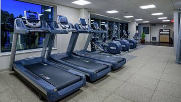 A gym with multiple treadmills, a large window, and a clock on the wall.