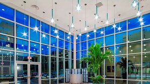 A spacious lobby with large windows, a central plant, and multiple hanging lights. - DoubleTree by Hilton Hotel Bristol, Connecticut (Bristol)