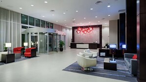 A modern lobby with a reception desk, seating area, and a large decorative light fixture. - DoubleTree by Hilton Hotel Bristol, Connecticut (Bristol)