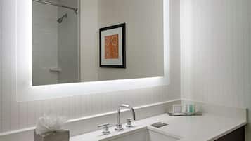 Une salle de bain moderne avec un grand miroir, un meuble-lavabo blanc et un meuble sombre.