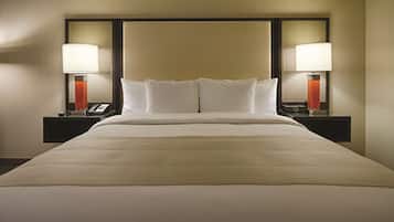 Una camera d'albergo con un letto grande, due comodini con lampade e una testiera.