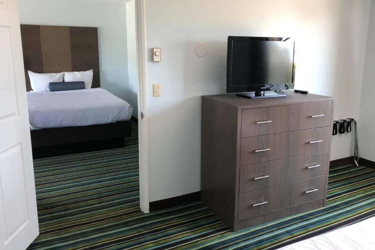 Ein Hotelzimmer mit einem Bett, einem Fernseher auf einem Schrank und einem Streifenmuster-Teppich.