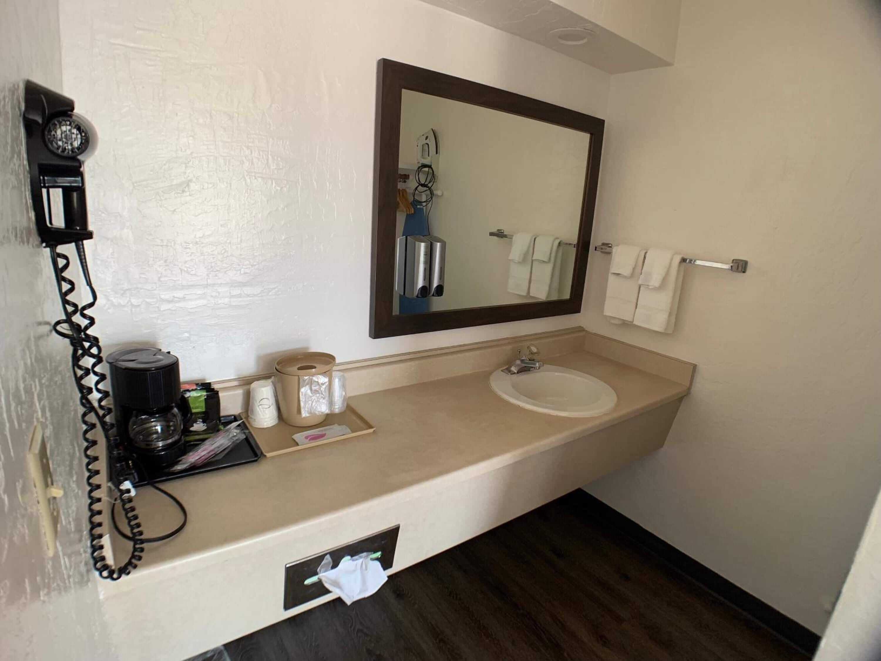 A hotel bathroom with a sink, mirror, towel rack, and a telephone.