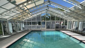 A clear swimming pool with a glass ceiling, surrounded by a brick border, and a 3 ft depth marker. - Brookings Inn Resort (Brookings)