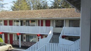 A motel with a two-story structure, a parking lot, and a car parked in front. - Brookings Inn Resort (Brookings)