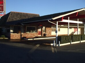 A building with a brick facade, a covered parking area, and a sign indicating an office and gift shop.