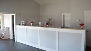 A reception desk with a white counter, a red lamp, and a vase with flowers. - Brookings Inn Resort (Brookings)