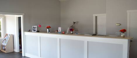 A reception desk with a white counter, a red lamp, and a vase with flowers.
