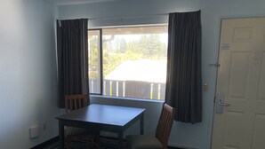 A room with a window, a table, two chairs, a door, and a striped carpet. - Brookings Inn Resort (Brookings)