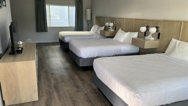 A hotel room with three beds, a desk, and a television. - Brookings Inn Resort (Brookings)